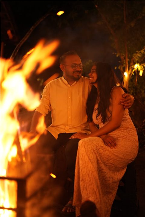 Akshay and Hansa seated together beside a glowing bonfire