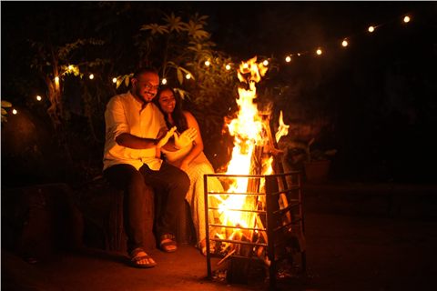 Akshay and Hansa smiling in warm firelight