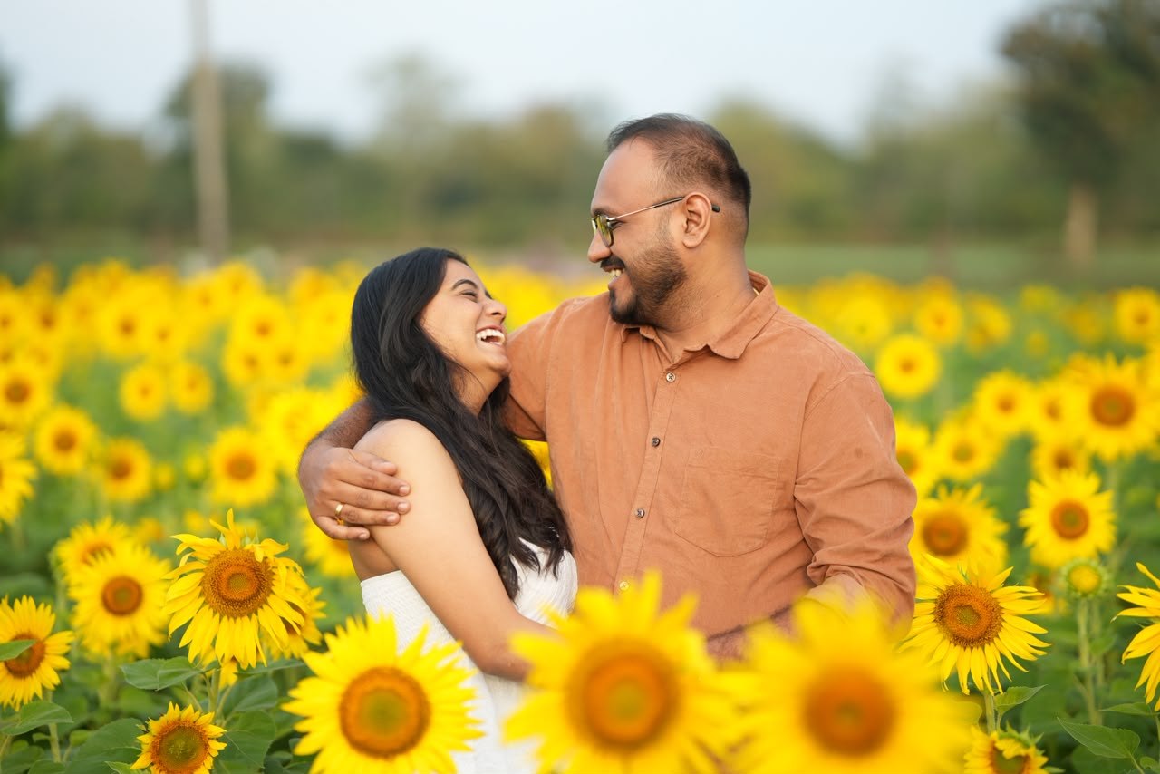 Akshay and Hansa smiling together in a field of sunflowers