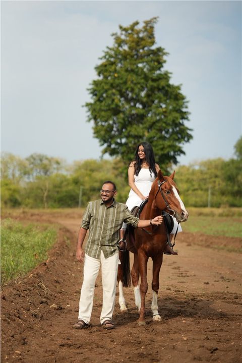 Akshay and Hansa with a horse beneath a countryside tree